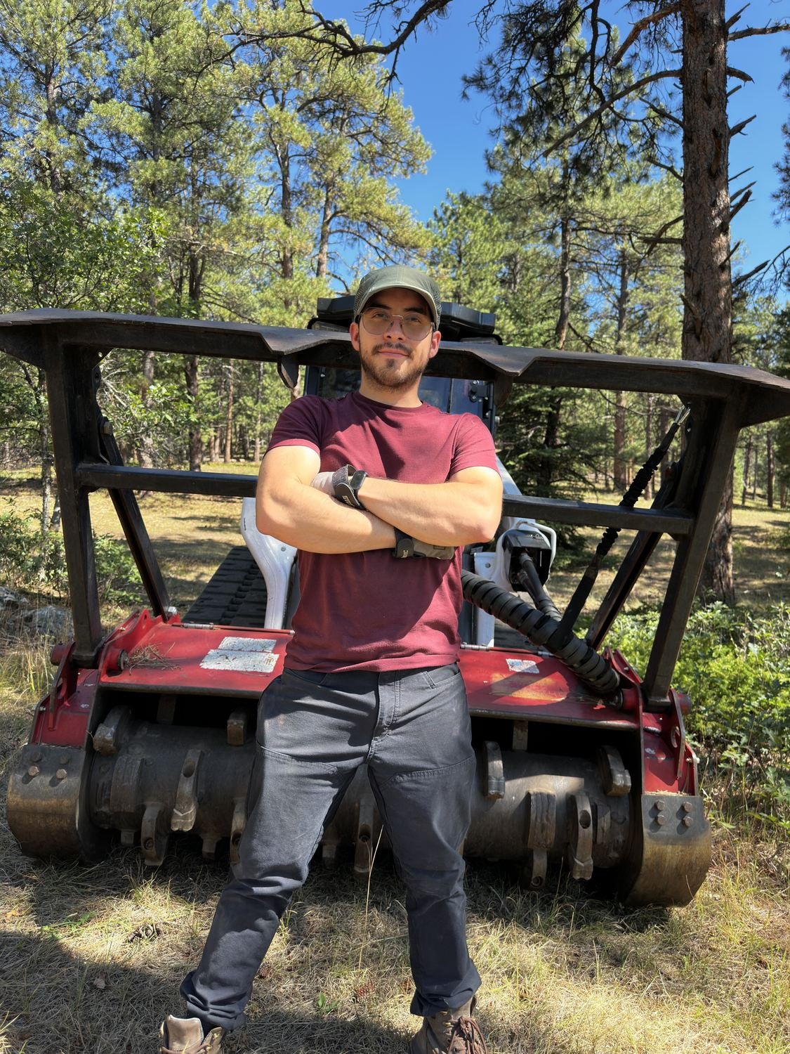 Daniel Sunderland Fernandez, founder of Blazeguard, standing in front of the Bobcat T86 compact track loader and forestry mulching head