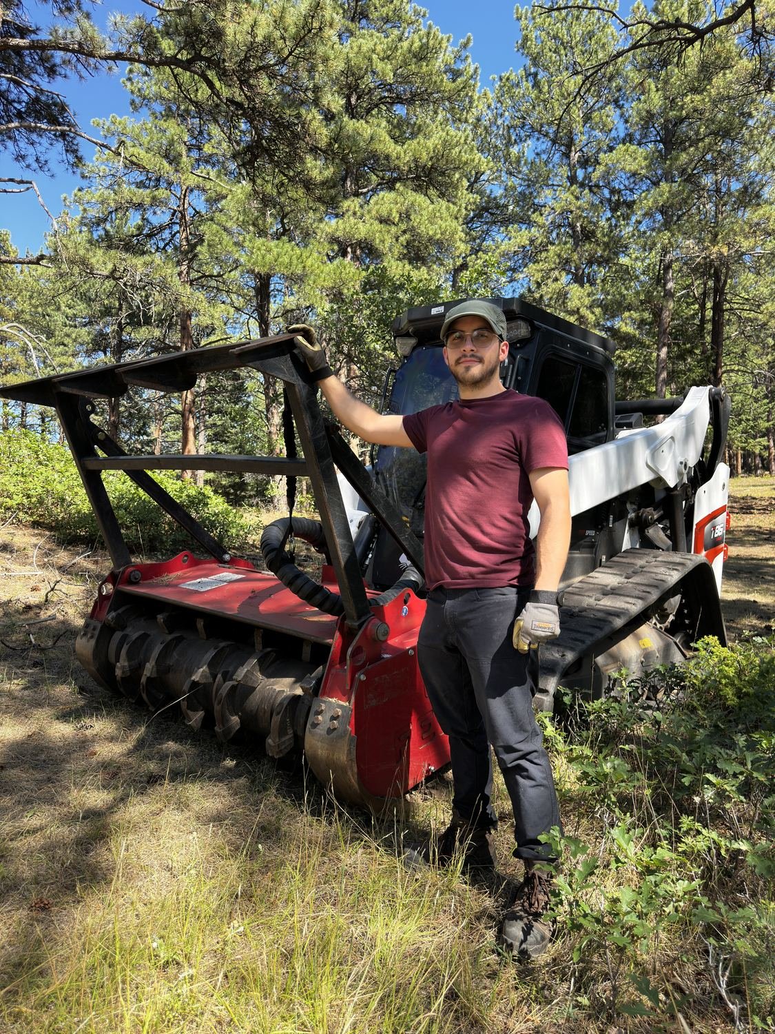 Daniel Sunderland Fernandez of Blazeguard beside the Bobcat T86 track loader and forestry mulching head that performs the work